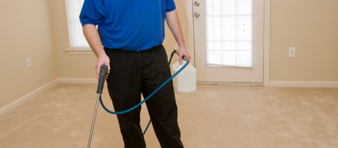 Man cleaning carpet with commercial cleaning equipment, He is treating stains before using steamer
